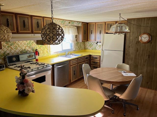 7377 Birch Dr, Port Hope, MI 48468 - kitchen with white appliances, a sink, under cabinet range hood, light wood finished floors, and light countertops