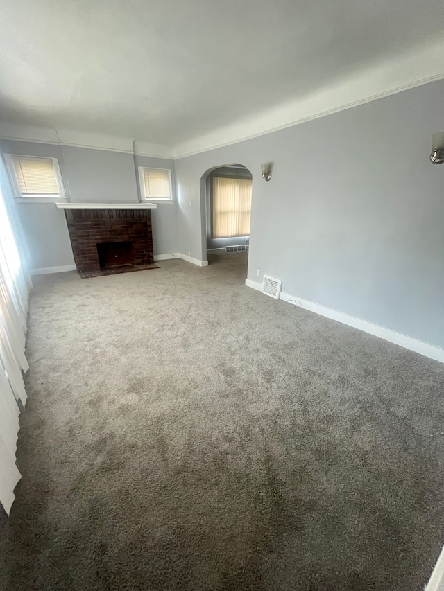 unfurnished living room with carpet floors and a brick fireplace