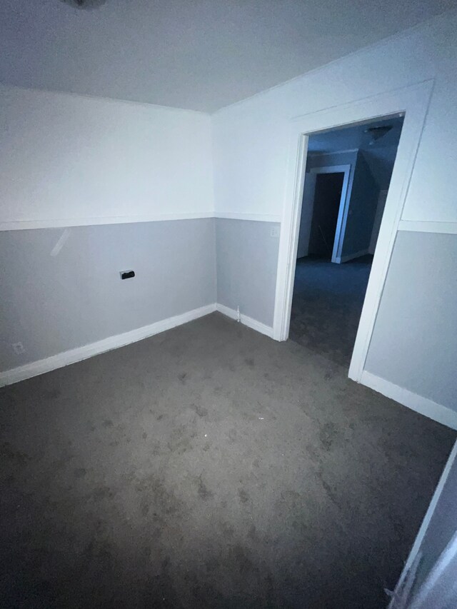 unfurnished room with dark colored carpet