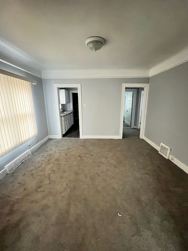 spare room featuring dark carpet and crown molding