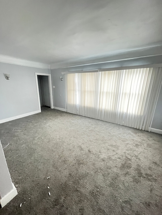 unfurnished room with dark colored carpet and a healthy amount of sunlight