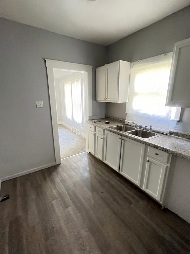 kitchen with sink, white cabinets, and dark wood-type flooring