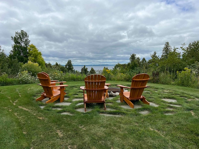 view of play area with a lawn, a fire pit, and a water view