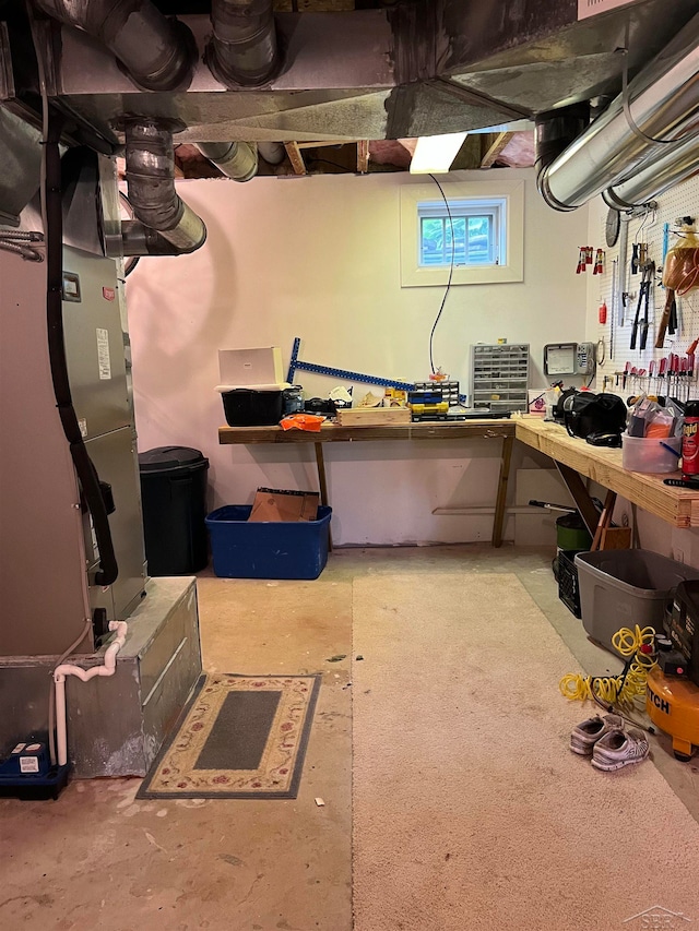 basement featuring a workshop area and heating unit