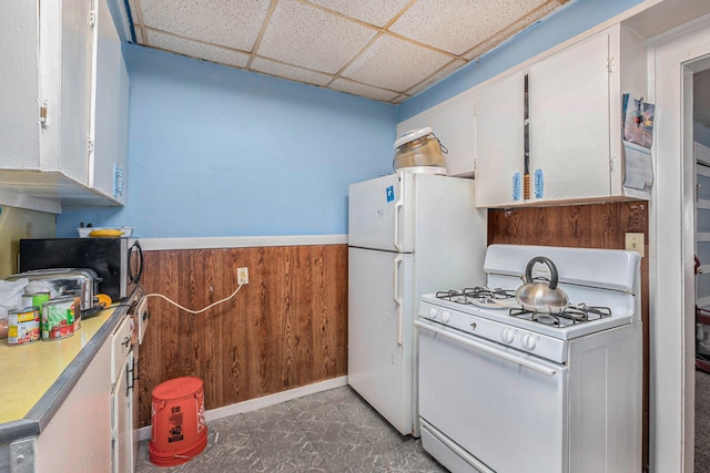 kitchen with white cabinets, a drop ceiling, white gas range oven, and wooden walls