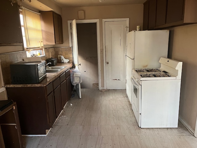 kitchen with backsplash, dark brown cabinetry, sink, and gas range gas stove