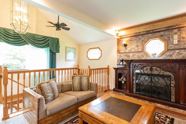 living room with vaulted ceiling with beams, a fireplace, and ceiling fan with notable chandelier