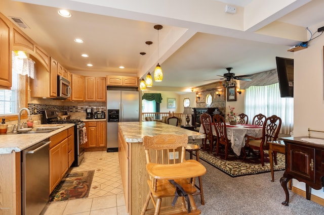 kitchen with appliances with stainless steel finishes, ceiling fan, sink, decorative light fixtures, and a center island