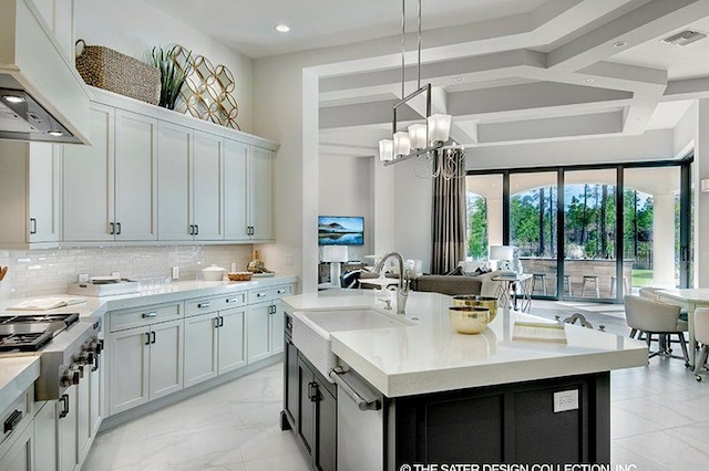 kitchen with decorative backsplash, decorative light fixtures, a center island with sink, and white cabinetry