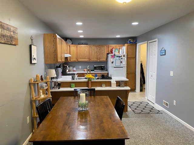 kitchen with a center island, sink, a kitchen breakfast bar, white refrigerator, and light carpet