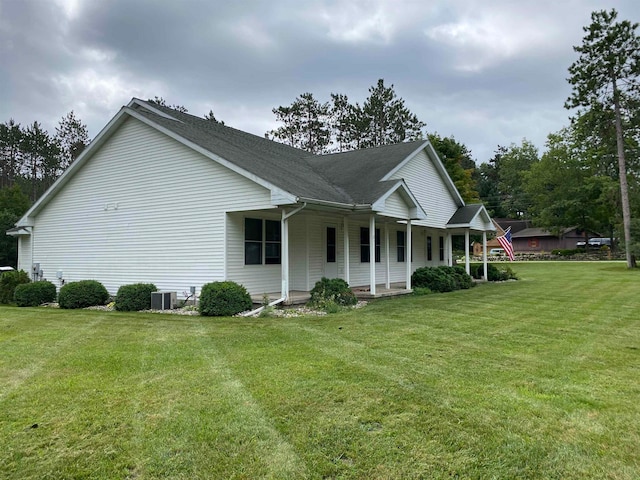 view of side of property with a yard and central AC