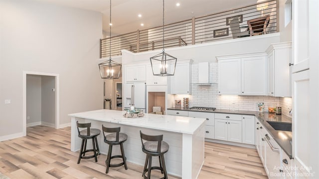 kitchen with a towering ceiling, white cabinets, decorative light fixtures, and a kitchen island