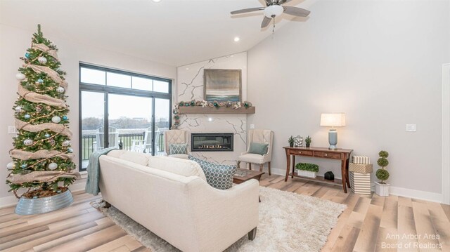 46 Gallery Pointe Dr, Saline, MI 48176 - living room featuring a glass covered fireplace, ceiling fan, wood finished floors, baseboards, and high vaulted ceiling