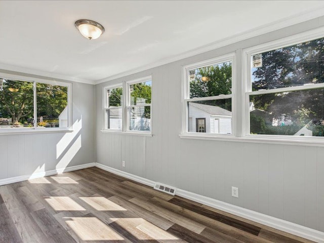 unfurnished room featuring wood walls, hardwood / wood-style floors, and ornamental molding