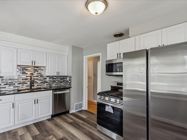 kitchen featuring white cabinetry, sink, stainless steel appliances, dark hardwood / wood-style flooring, and decorative backsplash