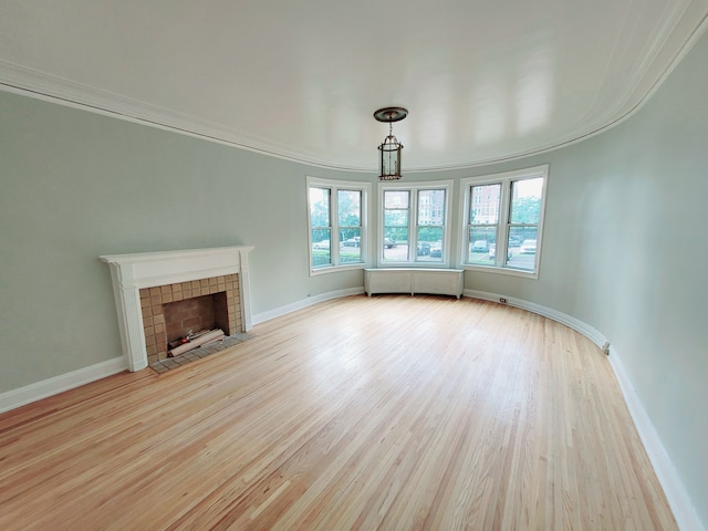 unfurnished living room with crown molding, a fireplace, light hardwood / wood-style floors, and radiator heating unit