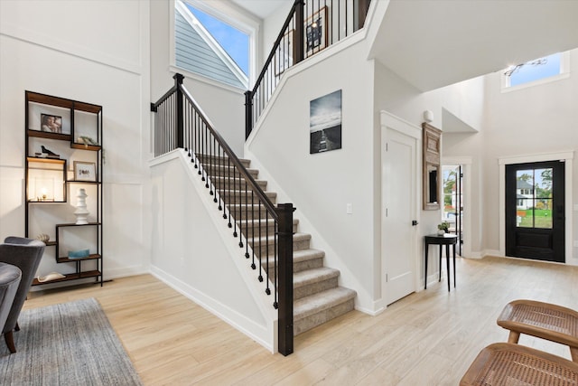 entrance foyer with a towering ceiling and light hardwood / wood-style floors