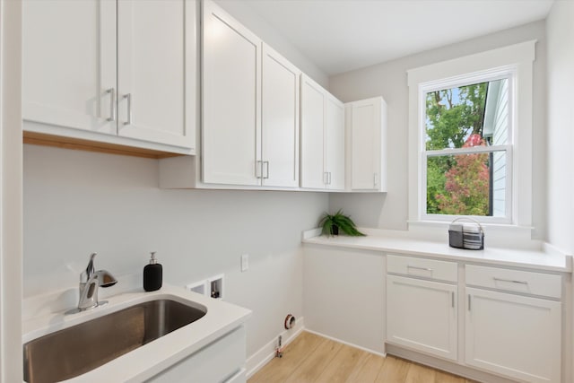 laundry area with washer hookup, light hardwood / wood-style floors, cabinets, and sink