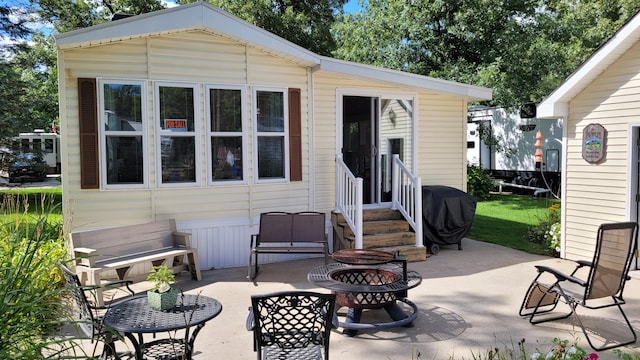 back of property with a patio and an outdoor fire pit