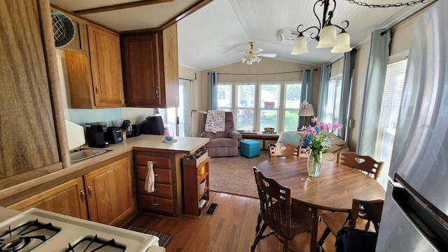 kitchen with a healthy amount of sunlight, lofted ceiling, kitchen peninsula, and hanging light fixtures