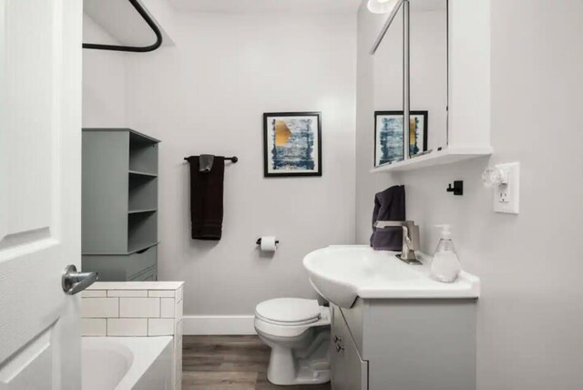 bathroom featuring hardwood / wood-style floors, a bathtub, toilet, and vanity