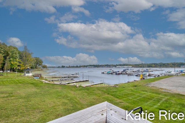 view of dock with a yard and a water view