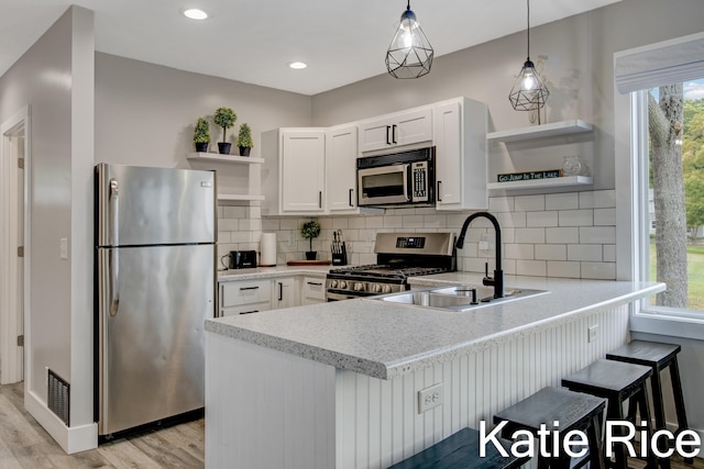 kitchen with white cabinets, a kitchen breakfast bar, sink, appliances with stainless steel finishes, and kitchen peninsula