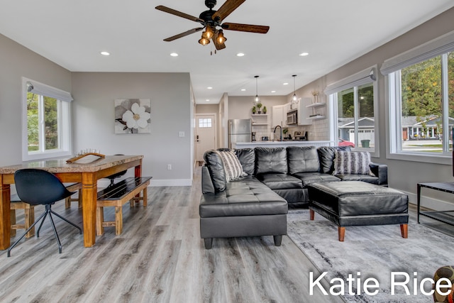 living room featuring ceiling fan, light wood-type flooring, and sink