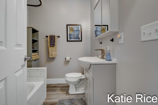 bathroom with toilet, vanity, a bath, and hardwood / wood-style flooring