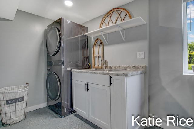 washroom featuring stacked washer and dryer, cabinets, and sink