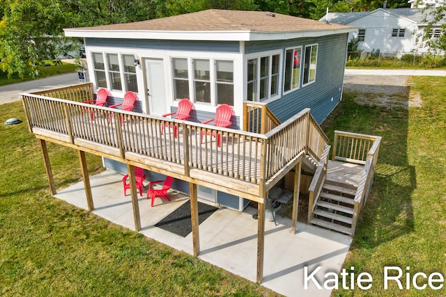 exterior space with a deck, a patio, a shingled roof, stairs, and a lawn