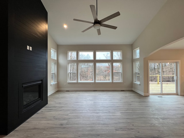 unfurnished living room with ceiling fan, a healthy amount of sunlight, a fireplace, and light hardwood / wood-style flooring