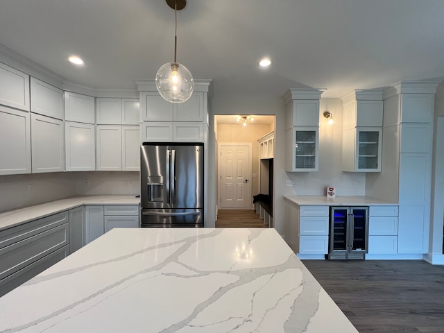 kitchen with light stone countertops, dark wood-type flooring, beverage cooler, stainless steel refrigerator with ice dispenser, and decorative light fixtures