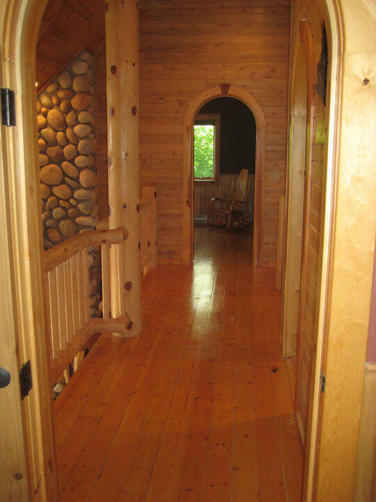 W4231 Wildwood Ln, Moran, MI 49760 - hall with arched walkways, hardwood / wood-style floors, and lofted ceiling