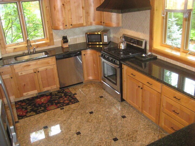 W4231 Wildwood Ln, Moran, MI 49760 - kitchen featuring stainless steel appliances, ventilation hood, a sink, granite tiled floors, and backsplash