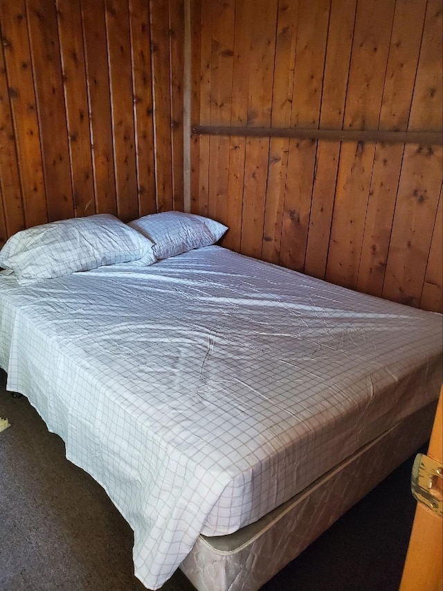 carpeted bedroom featuring wood walls