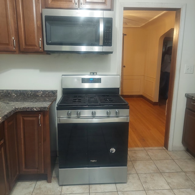 kitchen with dark stone countertops, light wood-type flooring, and appliances with stainless steel finishes