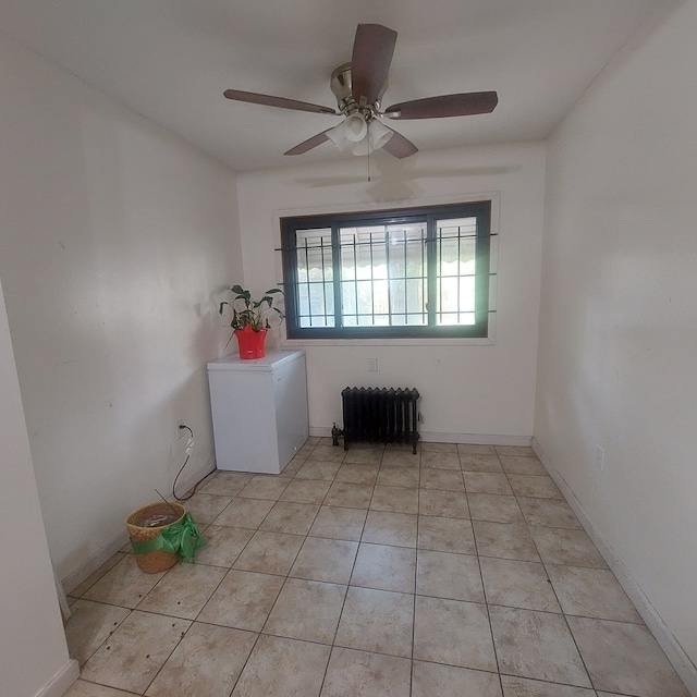 empty room with radiator heating unit, light tile patterned floors, and ceiling fan