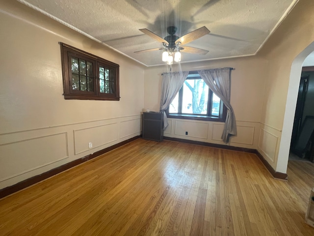 unfurnished room with ceiling fan, light hardwood / wood-style floors, and a textured ceiling