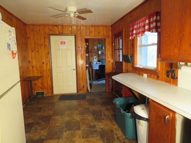 kitchen with ceiling fan, white refrigerator, and wooden walls