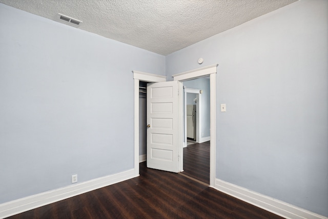 empty room with a textured ceiling and dark hardwood / wood-style floors