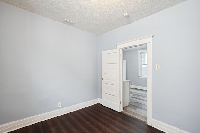 spare room with dark wood-type flooring and a textured ceiling