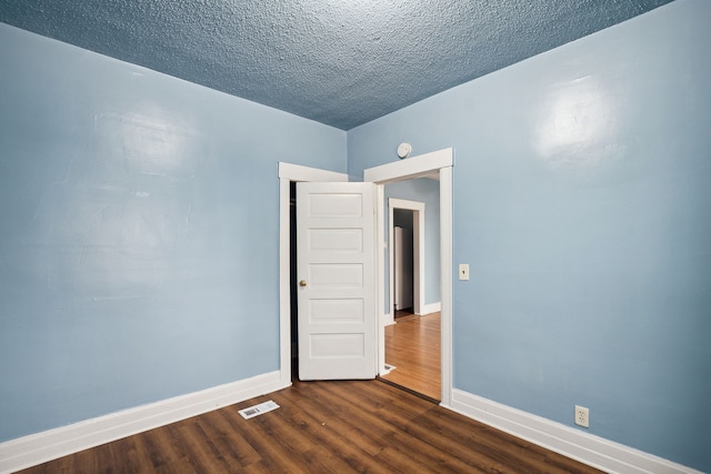 unfurnished room featuring dark hardwood / wood-style flooring and a textured ceiling