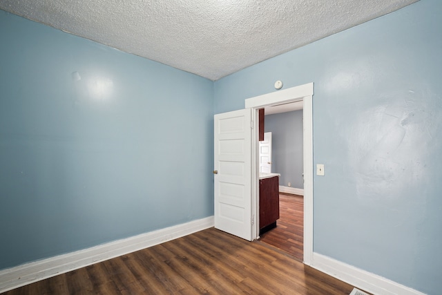 spare room featuring a textured ceiling and dark hardwood / wood-style floors