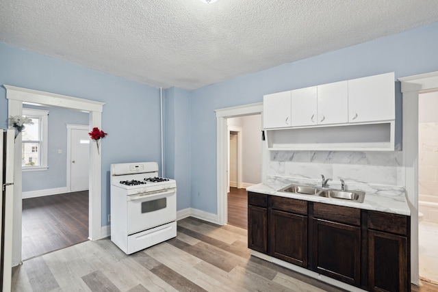 kitchen with sink, white range with gas stovetop, a textured ceiling, and light hardwood / wood-style floors