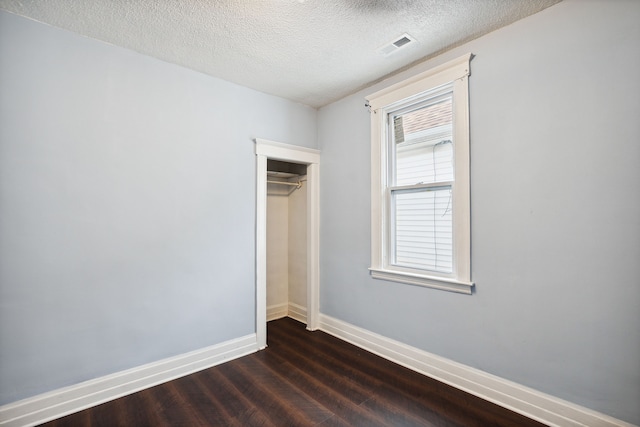 spare room with a textured ceiling and dark wood-type flooring