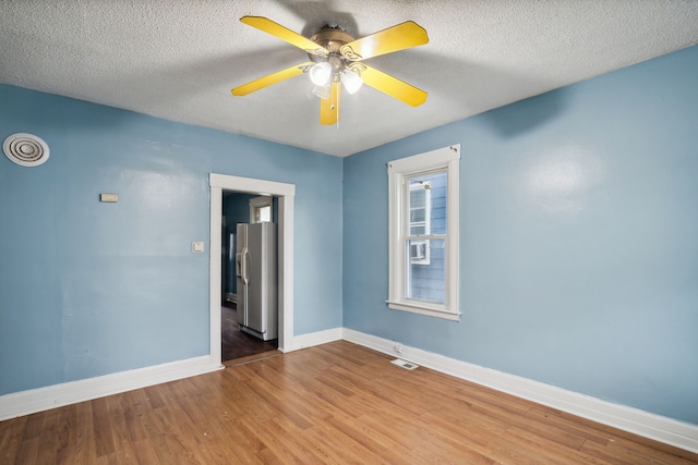 empty room with hardwood / wood-style floors, ceiling fan, and a textured ceiling