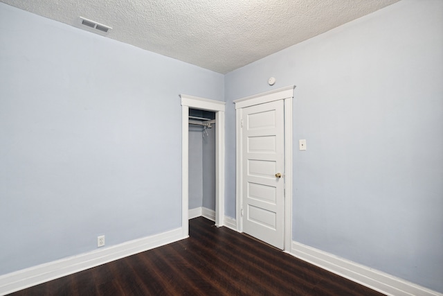 unfurnished bedroom with a textured ceiling, a closet, and dark hardwood / wood-style floors