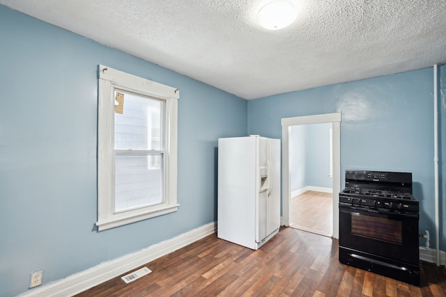 kitchen featuring a textured ceiling, black gas range oven, dark wood-type flooring, and white refrigerator with ice dispenser