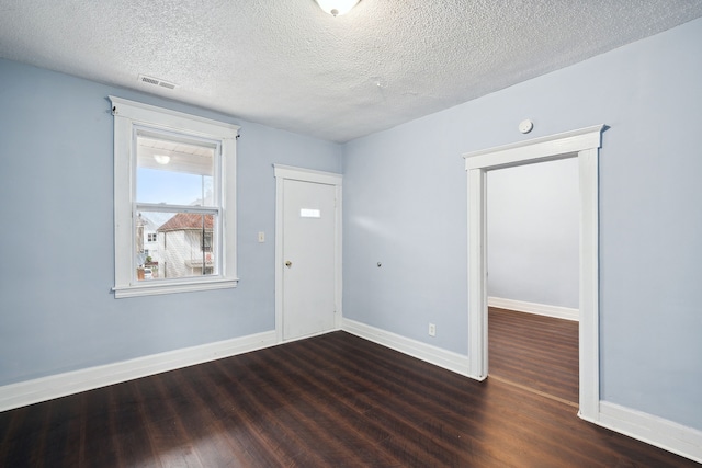 spare room with a textured ceiling and dark hardwood / wood-style floors